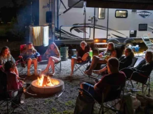 Guests relaxing around a campfire next to an RV
