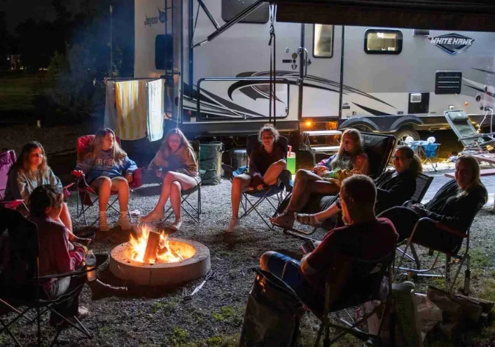 Guests relaxing around a campfire next to an RV